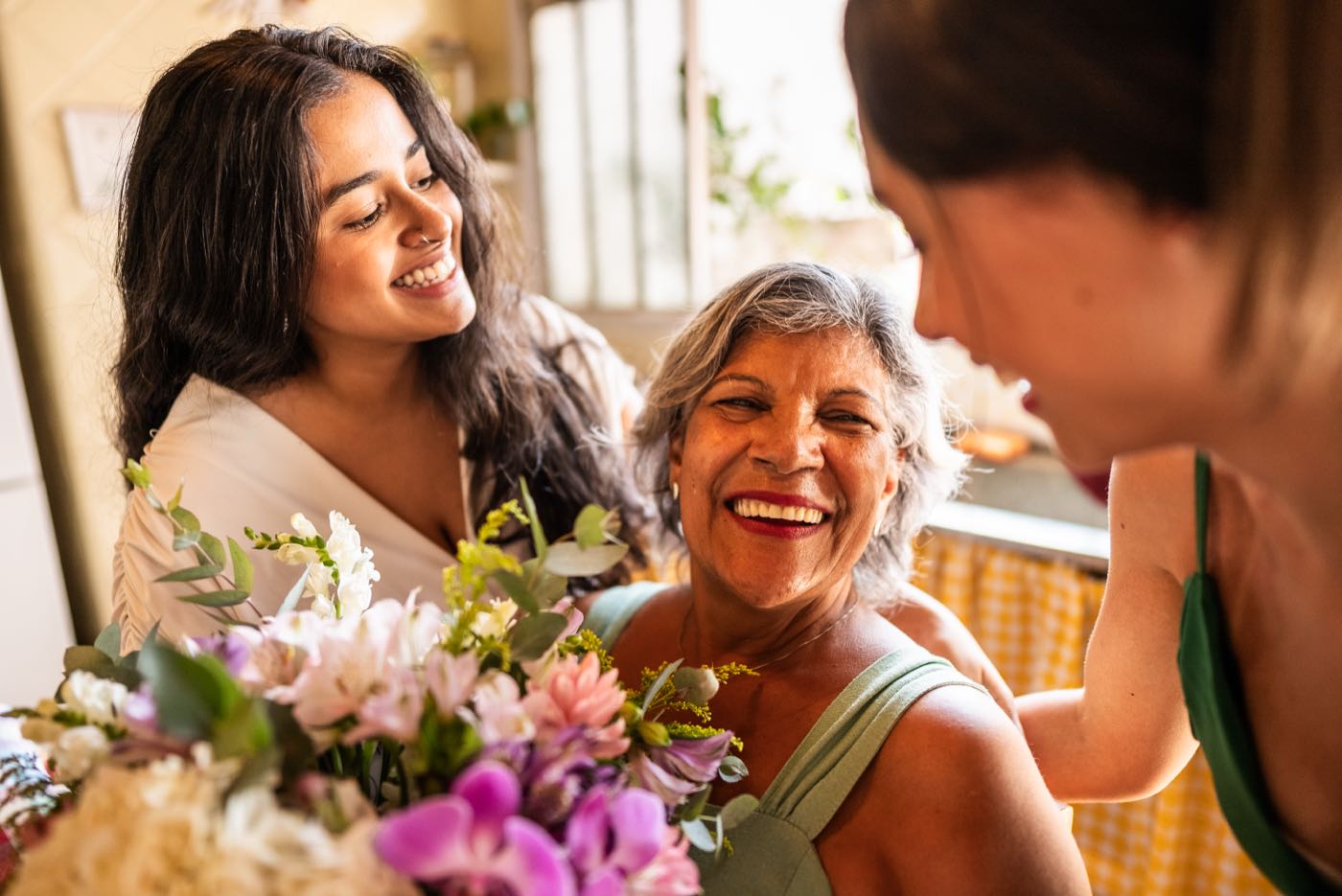 Three generations of women smiling together with a bouquet of flowers